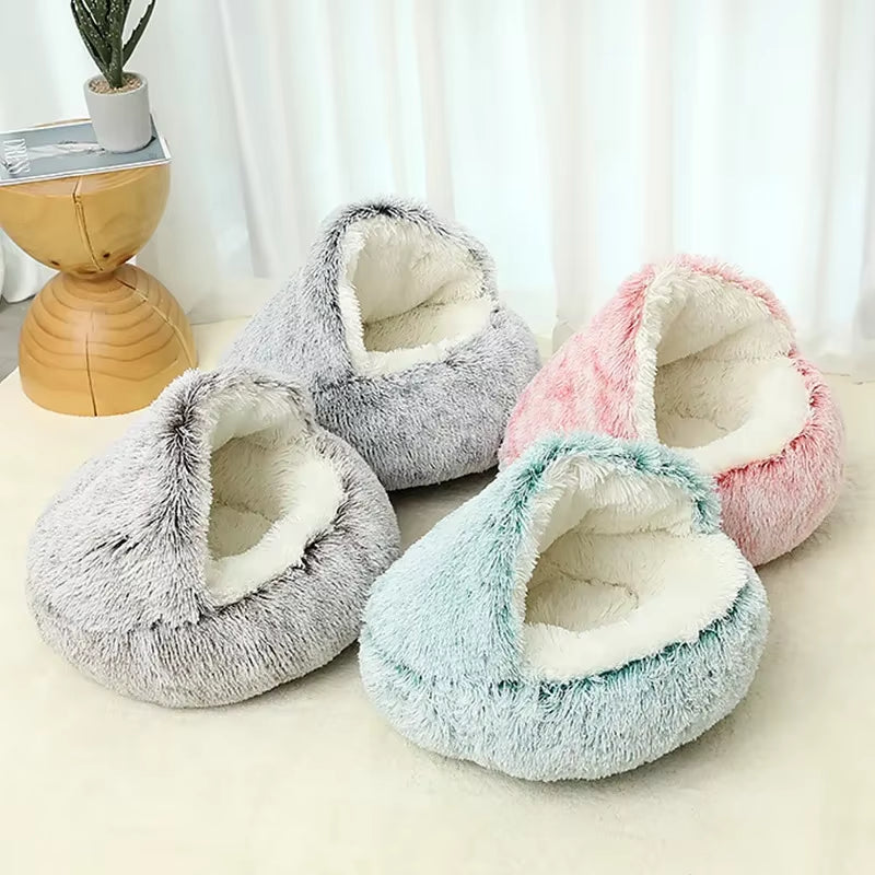 Four plush pet beds in gray, pink, and blue on a light surface with a white curtain background.