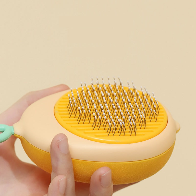 Yellow pet grooming brush held by a hand on a beige background
