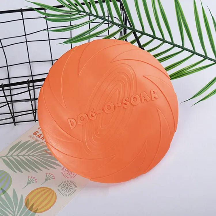 Orange dog toy with 'Dog-O-Soar' branding on a white surface with green leaves.