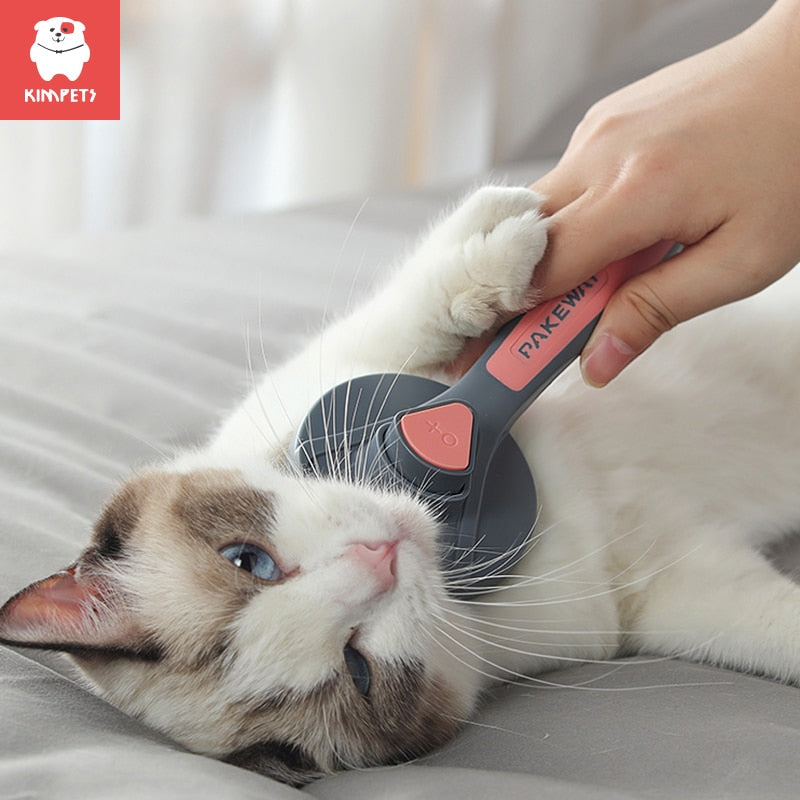 Cat being groomed with a pet brush by a person, with KIMPET logo in the corner.