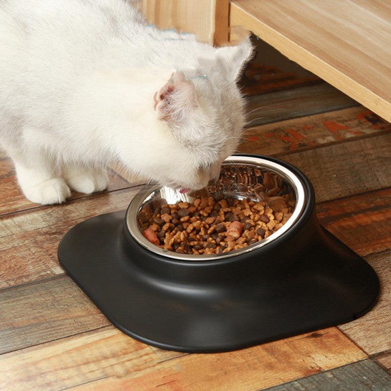 White cat eating from a metal bowl on a wooden floor